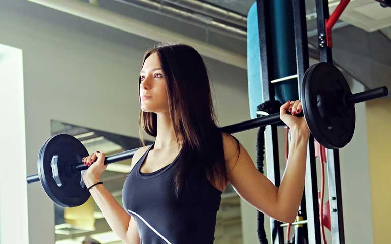 mujer joven levantando pesas en un gimnasio