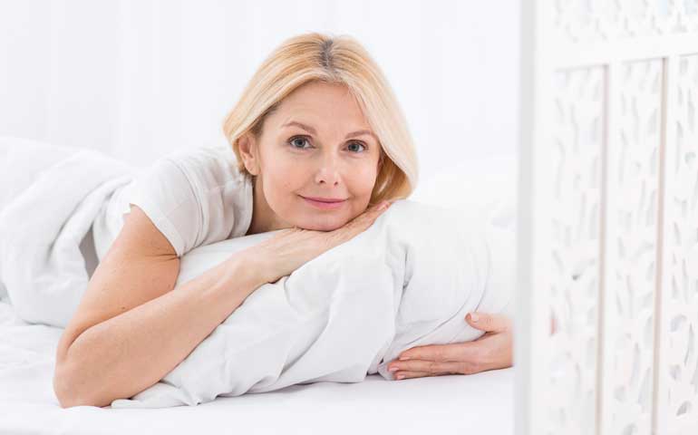 mujer de mediana edad en la cama mirando a cámara